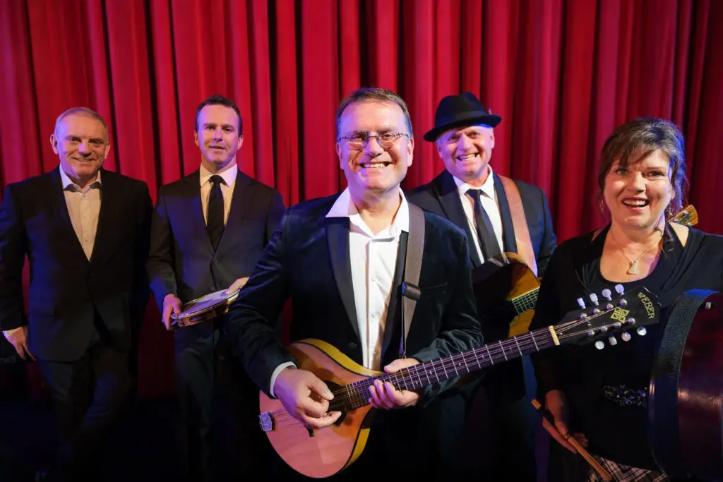 The Barra MacNeils performing with mandolin and guitar before a red stage curtain